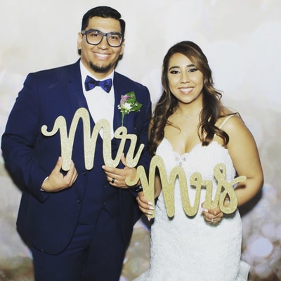 A new couple pairs up for a picture while holding Mr and Mrs letters